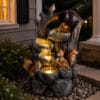 Squirrel outdoor water fountain with LED lights displayed in a backyard garden setting