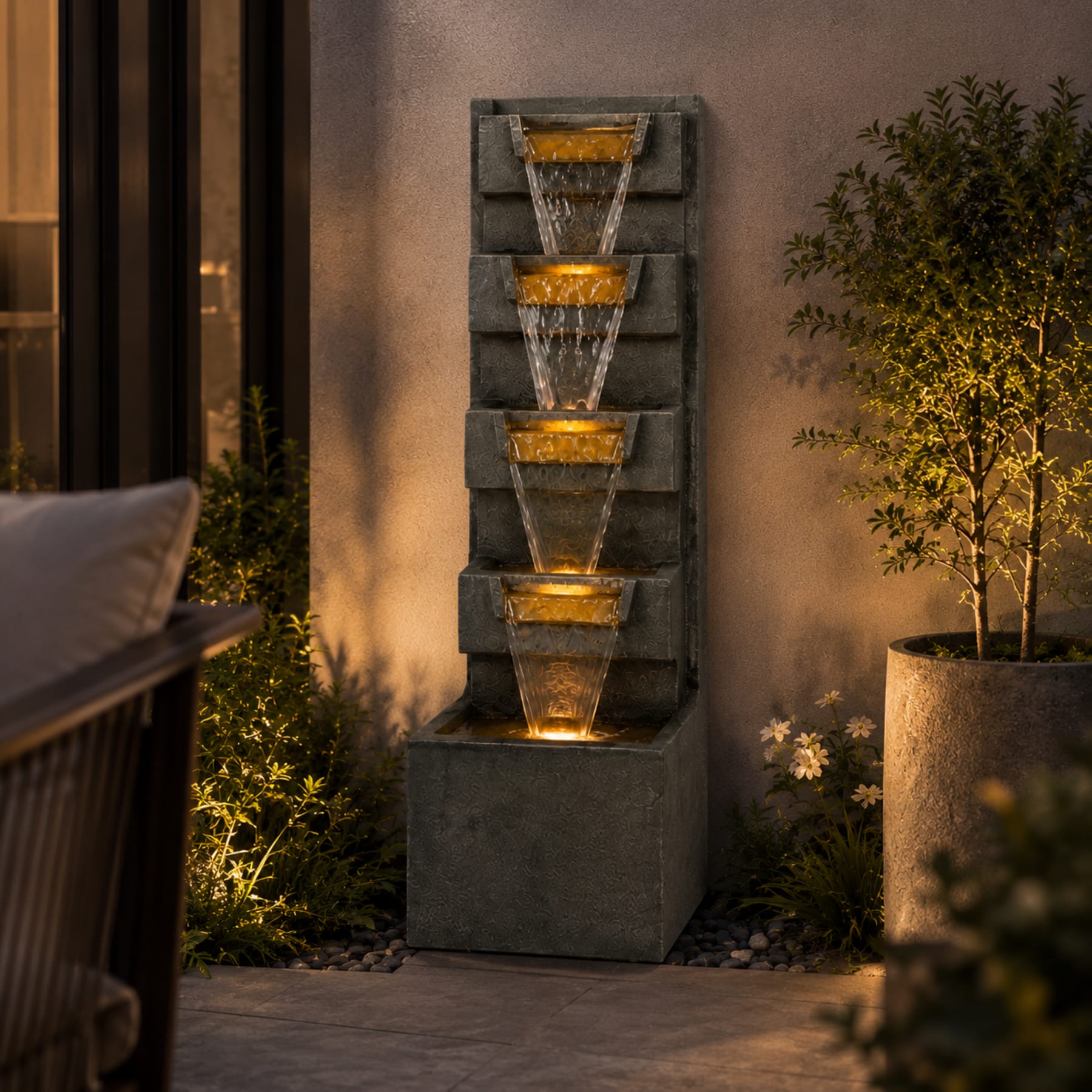 tall 4-tier outdoor waterfall fountain with warm LED lights beside a front entryway at night